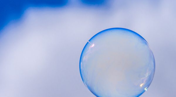 Eine Seifenblase vor einem blau-weißen Hintergrund.