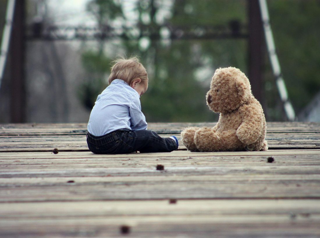 Ein Kind im Gespräch mit einem Teddybär.