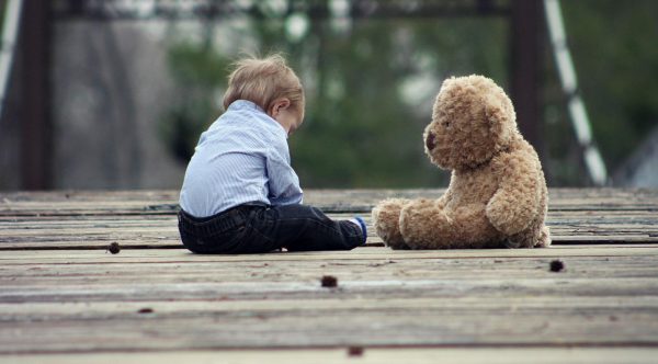 Ein Kind im Gespräch mit einem Teddybär.